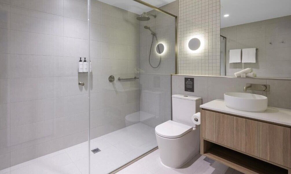 Un baño moderno con ducha de vidrio, inodoro y tocador con lavamanos.