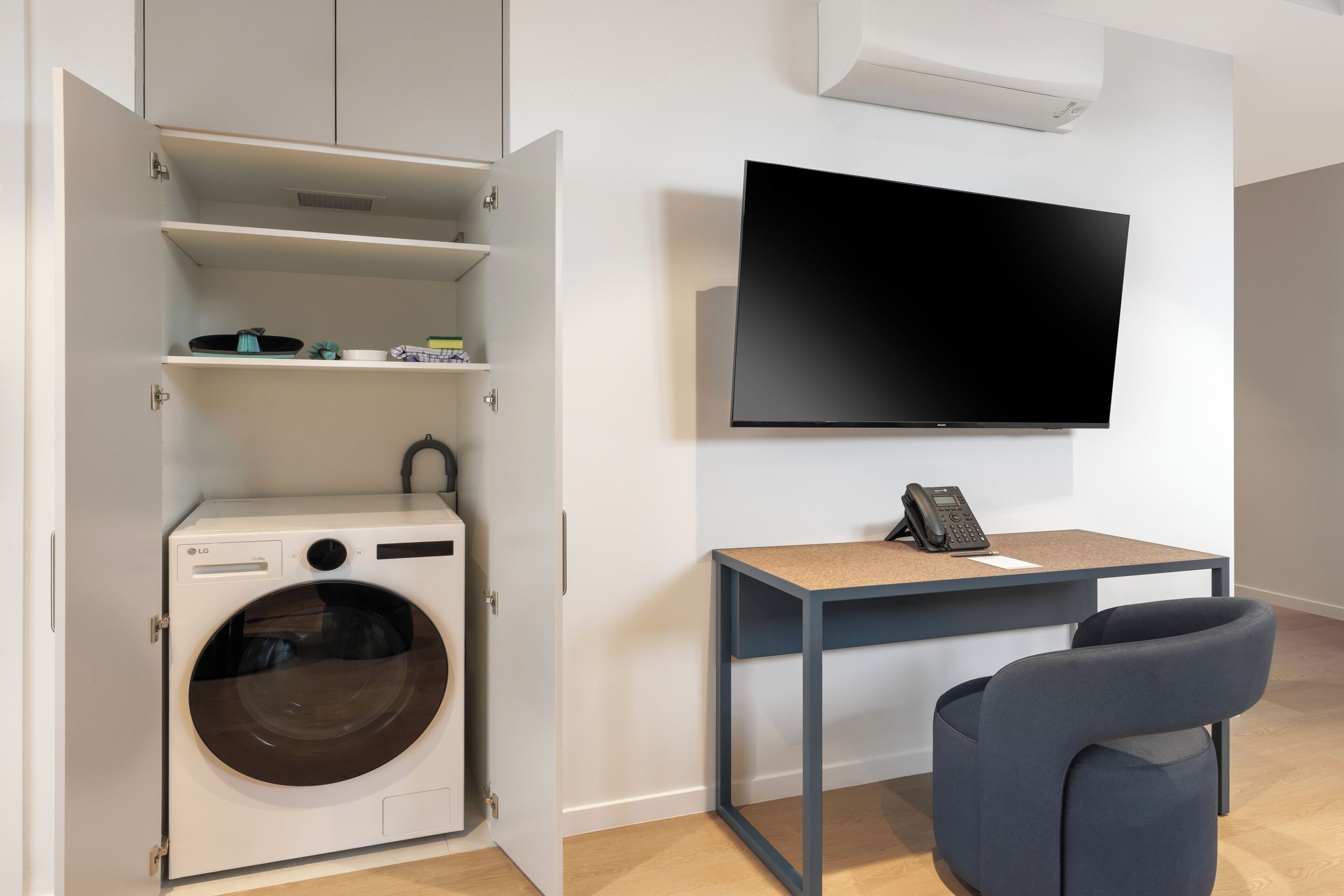 Une buanderie équipée d’un lave-linge, d’une table avec un téléphone et d’un téléviseur fixé au mur.