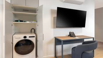 Une buanderie équipée d’un lave-linge, d’une table avec un téléphone et d’un téléviseur fixé au mur.