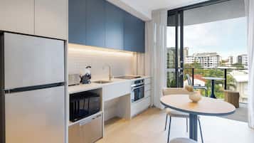 A modern kitchen with a refrigerator, microwave, and oven. There is a dining area with a table and chairs.