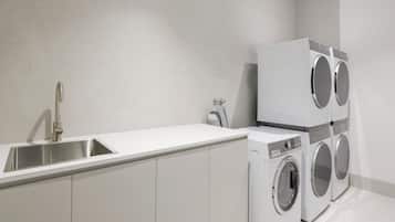 A modern kitchen with a stainless steel sink, white cabinets, and a built-in washing machine.
