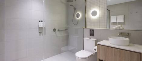 A modern bathroom with a glass-enclosed shower, a toilet, a sink, and a mirror.