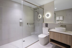 Un baño moderno con ducha envuelta en vidrio, inodoro, lavamanos y espejo.
