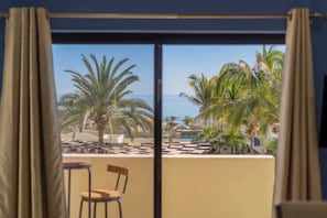 A balcony with a view of palm trees and a pool area.
