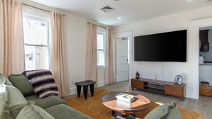 Una sala de estar moderna con un sofá verde, una mesa de centro y un televisor de pantalla plana montado en la pared.
