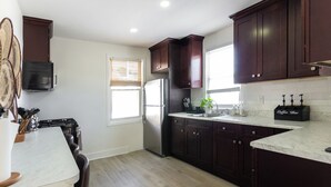 Una cocina moderna con armarios de madera oscura, un refrigerador de acero inoxidable, una encimera de mármol y una barra de café.