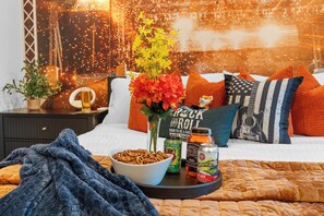 En pænt møbleret seng med en skål cornflakes, en dåse øl og en blomsterdekoration.