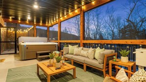 A cozy room with a sofa, coffee table, and a large window with a view of trees. - Poolside+Firepit+Hot Tub+Slides+Hidden Arcade (Hollister)