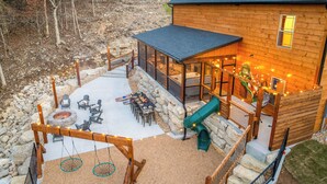 A wooden cabin with a covered patio, outdoor seating, a fire pit, and a slide. - Poolside+Firepit+Hot Tub+Slides+Hidden Arcade (Hollister)