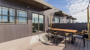 Eine moderne Außenpatio mit Holztisch und -stühlen, großen Fenstern und Blick auf die Stadt.
