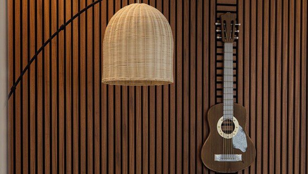 Ein modernes Wohnzimmer mit einer Wand aus Holzlatten, einer Hängelampe und einer Gitarre.