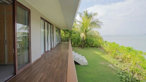 A modern building with large sliding glass doors, a wooden deck, and a view of the sea. - Riahi Villas by Swiss-Belhotel, Nirup Island (Nirup Island)