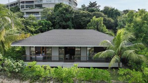 A modern building with a flat roof, surrounded by lush greenery and a stone wall. - Riahi Villas by Swiss-Belhotel, Nirup Island (Nirup Island)