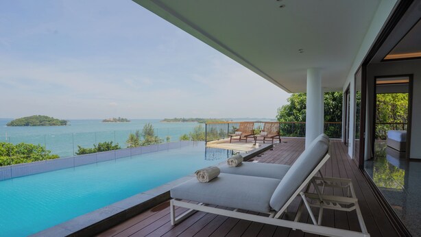 A wooden deck with a pool, two lounge chairs, and a view of the sea and islands. - Riahi Villas by Swiss-Belhotel, Nirup Island (Nirup Island)
