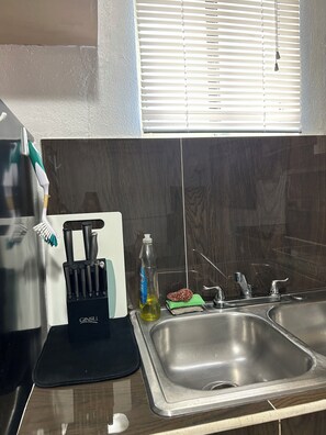 A kitchen with a stainless steel sink, a knife block, a bottle of dish soap, and a green cloth. - Charming 1-bedroom apartment with AC in central Hagåtña (Hagåtña)