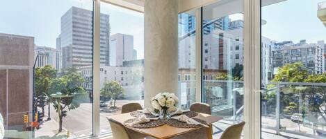 Una habitación moderna con ventanas amplias, una mesa redonda con sillas y un jarrón con flores blancas.