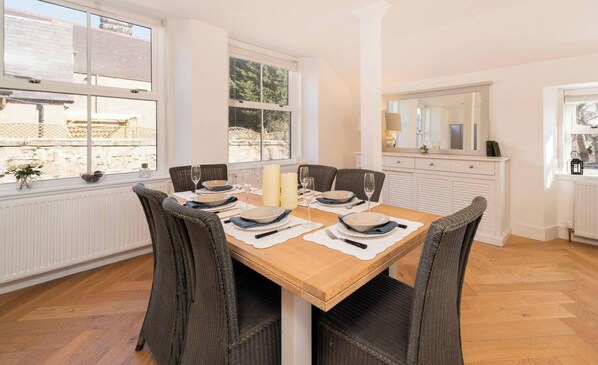 Een eetruimte met een houten tafel voor vier personen, omringd door rieten stoelen.