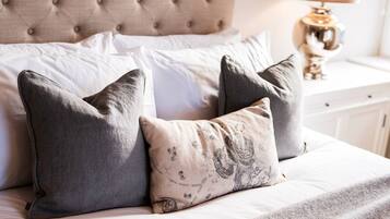 A bed with a tufted headboard, two pillows, and a bedside table with a lamp.