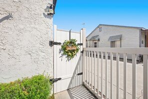 A white gate with a 'welcome' sign and a wreath, leading to a house with a white exterior and a window with shutters. - Charming Garden Grove Studio • Private Entry • 10 Min to Disneyland (Garden Grove)
