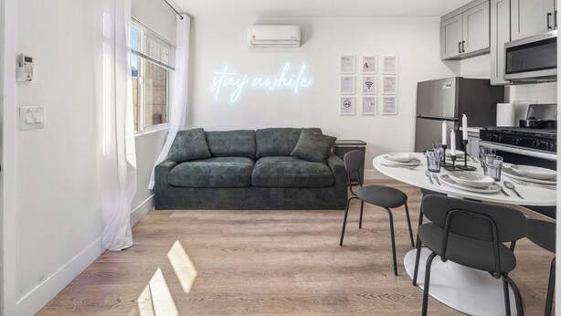 Ett modernt kök med en matplats, en grön soffa och en neonreklamskylt.