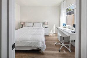 A modern bedroom with a bed, bedside tables, a desk, and a window. - Charming Garden Grove Studio • Private Entry • 10 Min to Disneyland (Garden Grove)