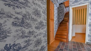 A room with patterned wallpaper, a wooden staircase, and a tiled floor. - Léo - BAR SUR AUBE - Gîte (BAR SUR AUBE)