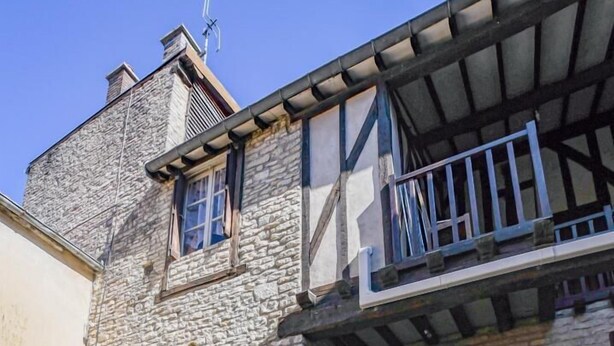 A stone building with a balcony, a wooden door, and a cobblestone courtyard. - Léo - BAR SUR AUBE - Gîte (BAR SUR AUBE)