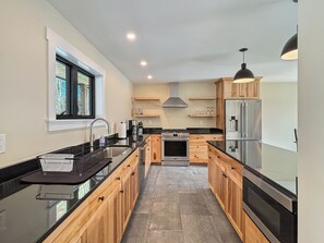 Una cocina moderna con armarios de madera, un refrigerador de acero inoxidable y una encimera negra.