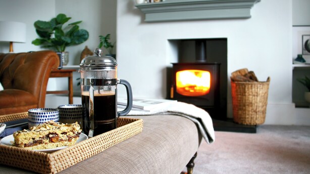 Ein gemütliches Wohnzimmer mit einer Kaffeemaschine, einer Speiseplatte und einem Fernseher im Hintergrund.