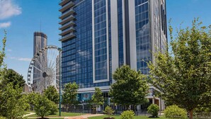 Un bâtiment moderne à la façade de verre, avec une grande roue et des espaces verts environnants.