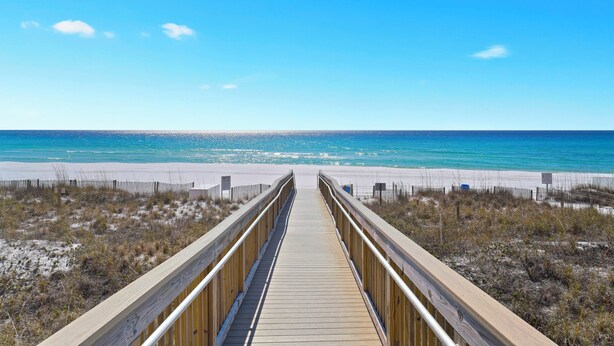 A wooden boardwalk leading to a beach with clear blue water and a sandy shore. - Beautiful Beachfront 3BR Condo with Pool! FREE Summer Beach Service! (Destin)