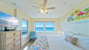A bedroom with a bed, a TV, a ceiling fan, a window with a view of the ocean, and a painting on the wall. - Beautiful Beachfront 3BR Condo with Pool! FREE Summer Beach Service! (Destin)
