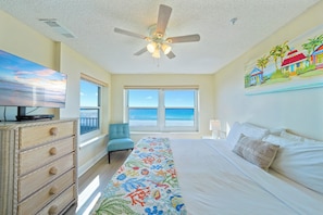 A bedroom with a bed, a TV, a ceiling fan, a window with a view of the ocean, and a painting on the wall. - Beautiful Beachfront 3BR Condo with Pool! FREE Summer Beach Service! (Destin)