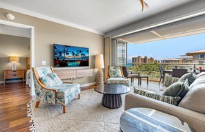 Un balcon spacieux offrant une vue sur les toits de la ville, un coin salon confortable avec un canapé et des fauteuils, et un téléviseur à écran plat fixé au mur.