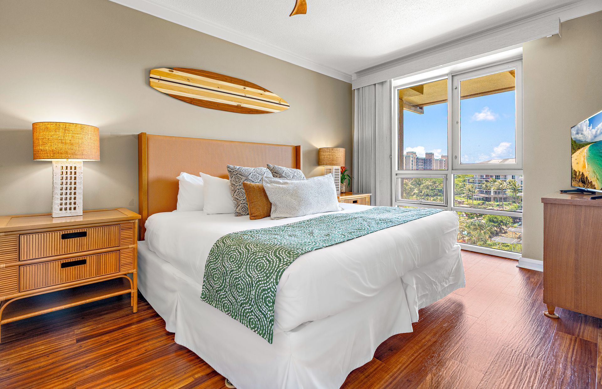 Hotelkamer met een groot bed, houten hoofdeinde, twee bedlampen, uitzicht op de stad en een balkon.