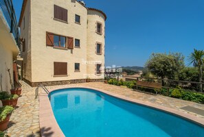 A two-story building with a swimming pool, stone flooring, and potted plants. - R-8 Apartment with beautiful sea views, great terrace and pool (Calella de Palafrugell)