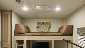 A compact room with a bunk bed, a TV, and built-in cabinets. - Come Settle in this cozy modern style RV, Nestled in the quiet country side. (Bushnell)