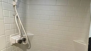 A small, white-tiled shower area with a handheld showerhead and a handheld shower attachment. - Come Settle in this cozy modern style RV, Nestled in the quiet country side. (Bushnell)