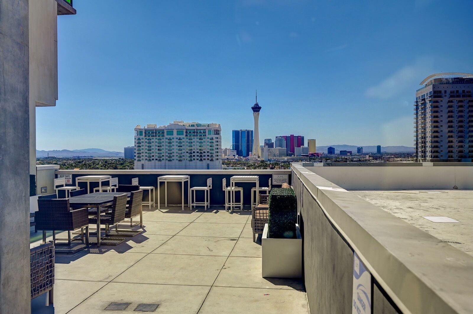 A rooftop terrace with outdoor seating, a view of the city skyline, and a prominent tower.
