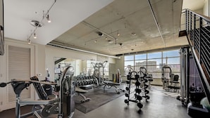 Ein Fitnessstudio mit unterschiedlichen Trainingsgeräten, großen Fenstern und Blick auf einen Turm.