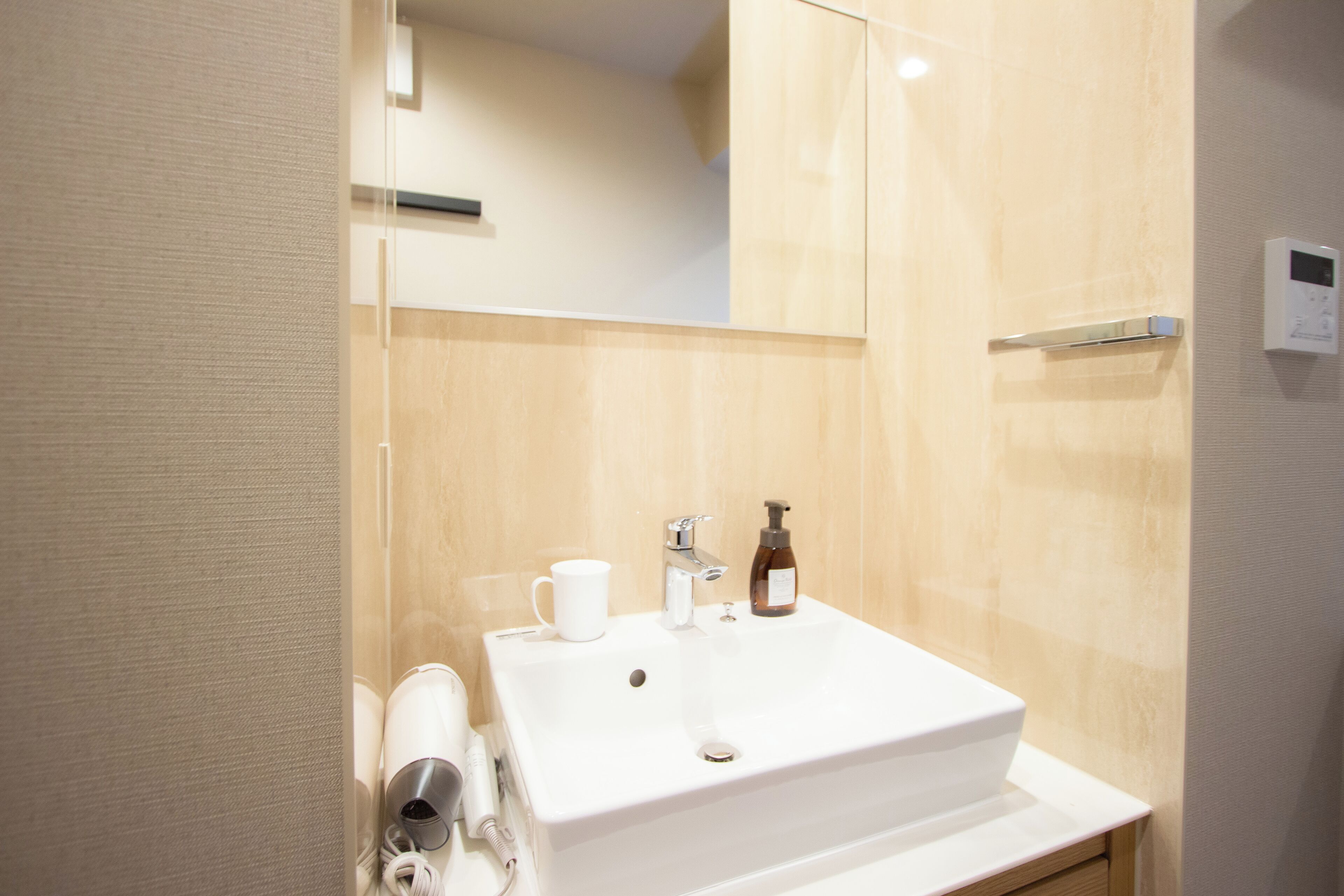 Un baño moderno con un lavabo blanco, un espejo y un mueble de tocador de madera.