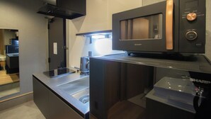 Una cocina moderna con microondas integrado, cafetera y pileta de acero inoxidable.