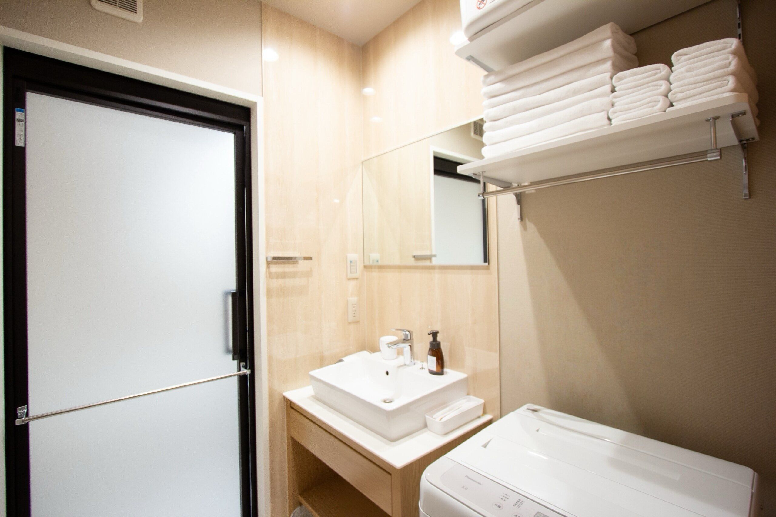 A bathroom with a white sink, a mirror, a towel rack, and a toilet.