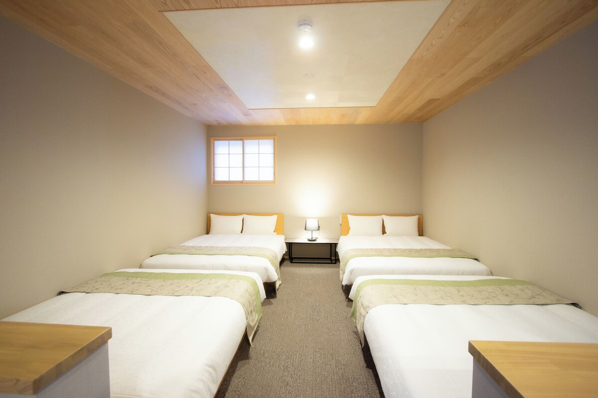 A hotel room with two single beds, a small window, and a ceiling light.