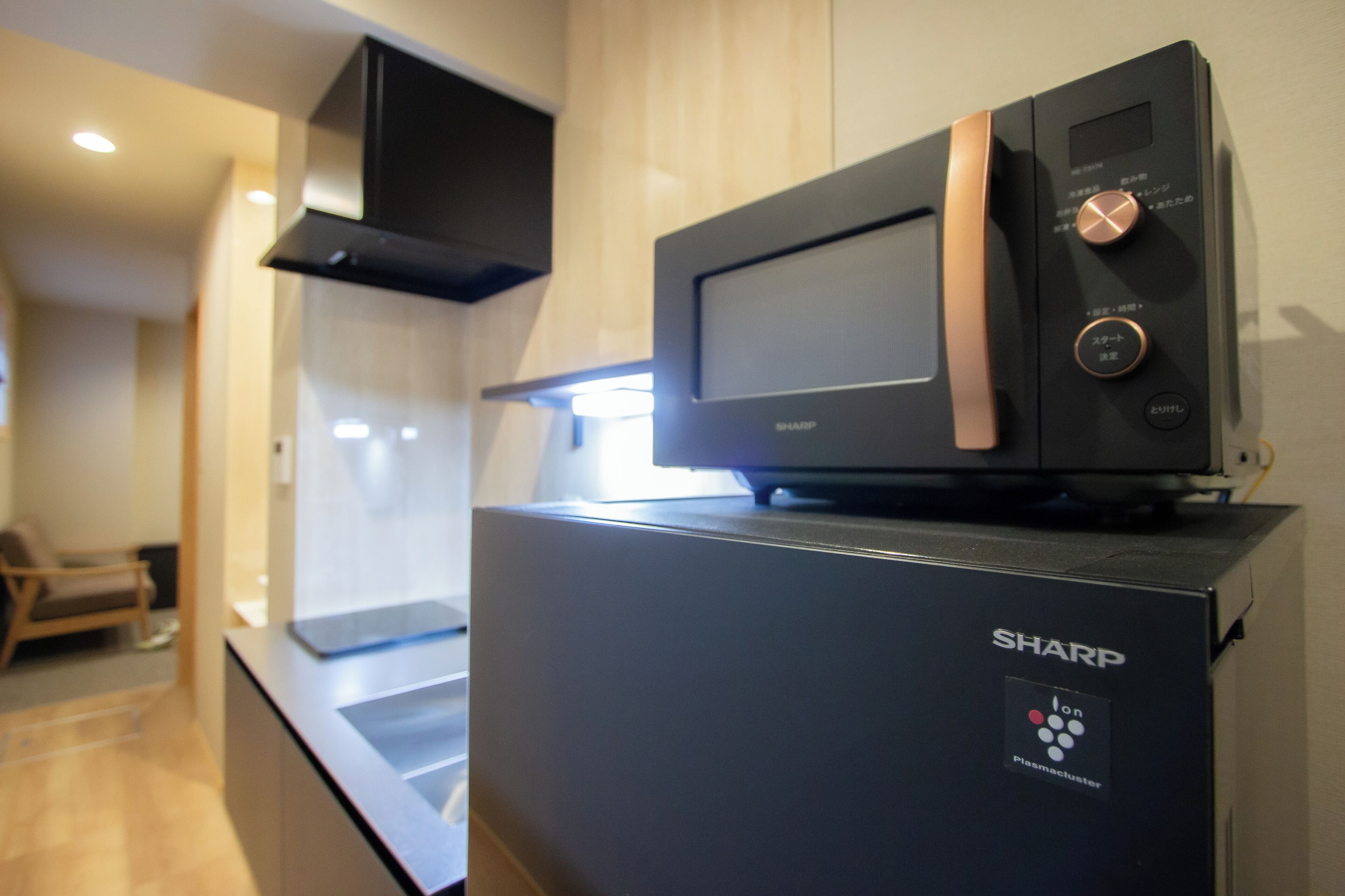 A kitchen with a microwave on top of a black Sharp refrigerator.