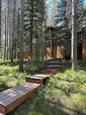 A wooden deck with benches leading to a cabin in a forest.