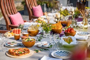Una mesa de comedor servida con diferentes platos, vasos y una pizza.