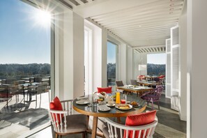 A dining area with a table set for breakfast, large windows, and a view of the outdoors. - Norbu The Montanna, Dharamshala - Ihcl Seleqtions (Dharamshala)