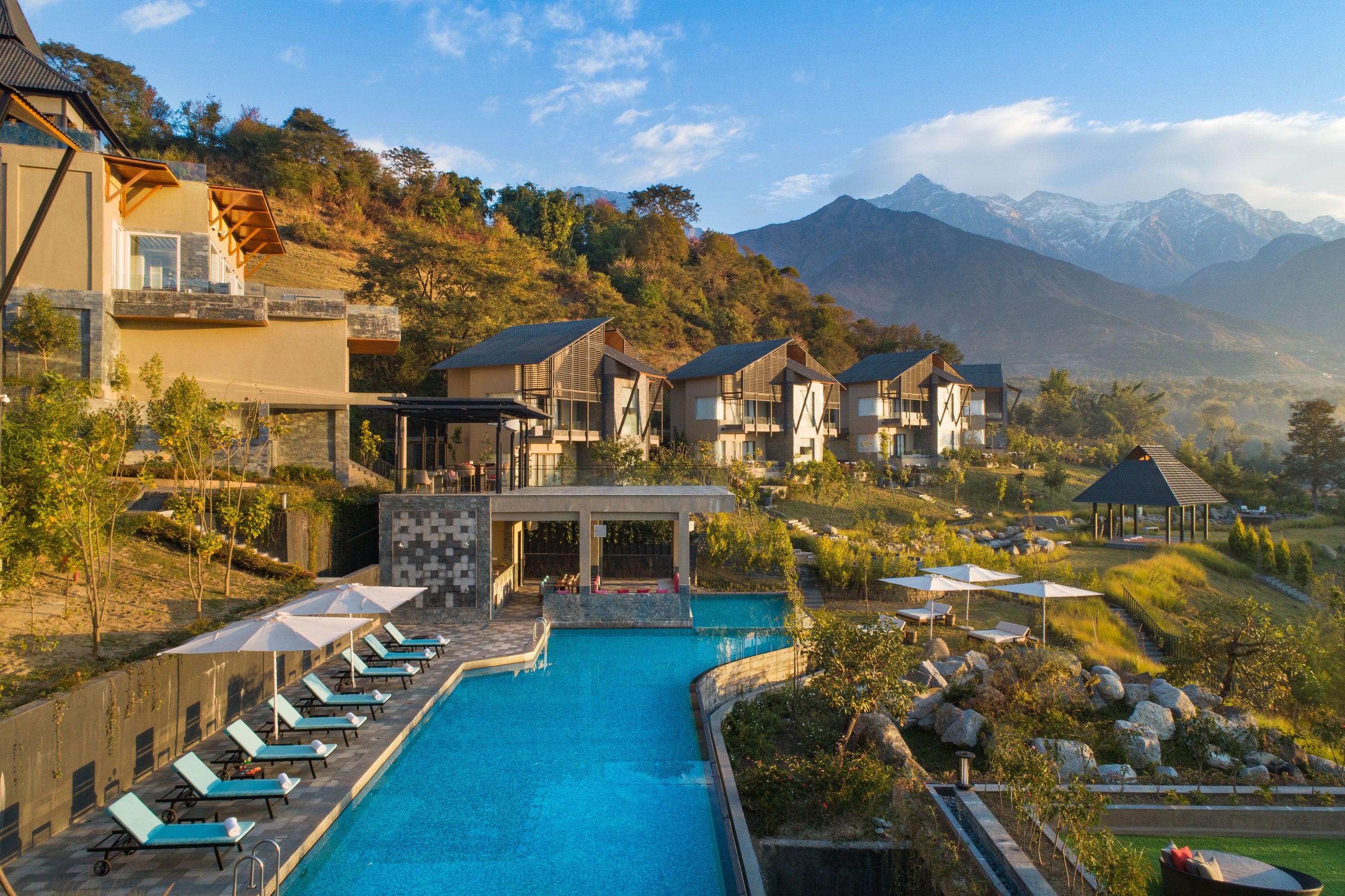 A resort with a swimming pool, lounge chairs, and mountain views.