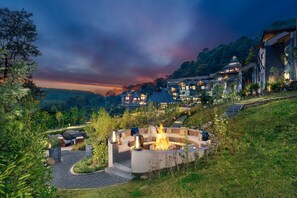 A modern outdoor seating area with a fire pit, surrounded by a stone wall and greenery. - Norbu The Montanna, Dharamshala - Ihcl Seleqtions (Dharamshala)